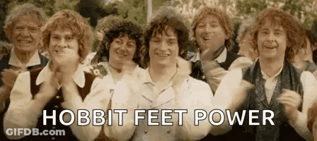 A Group Of People Are Standing Next To Each Other With Their Hands In The Air And The Words `` Hobbit Feet Power '' . GIF