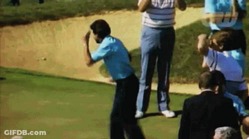 A Group Of People Are Standing On A Golf Course Watching A Man Hit A Golf Ball Out Of A Bunker . GIF