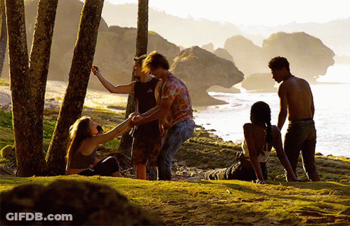 A Group Of People Are Standing On A Grassy Hill Near The Ocean GIF
