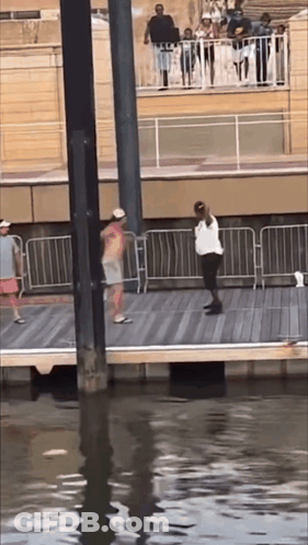 A Group Of People Are Standing On A Pier Overlooking The Water GIF