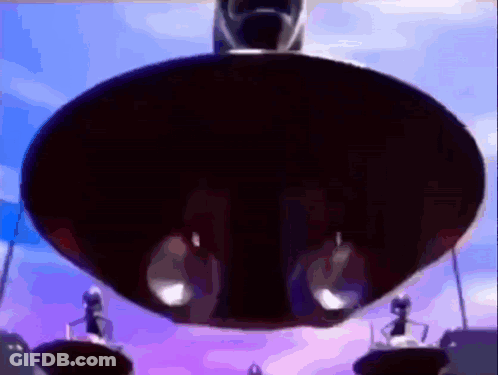 A Group Of People Are Standing On A Platform In Front Of A Large Black Object . GIF