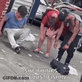 A Group Of People Are Standing On A Sidewalk And One Of Them Is Kneeling Down . GIF