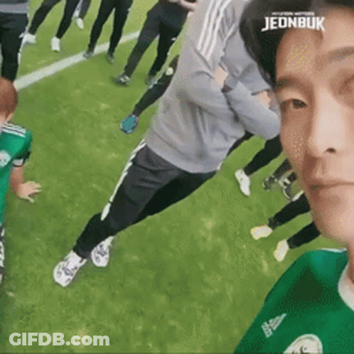 A Group Of People Are Standing On A Soccer Field And One Of Them Has The Word Jeonbuk On His Head . GIF