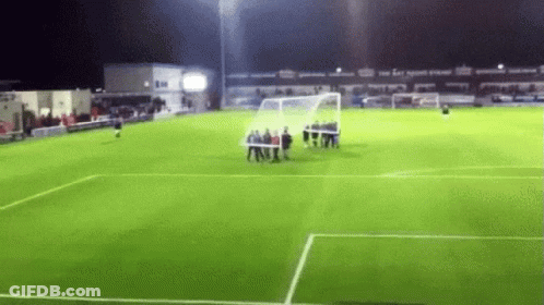 A Group Of People Are Standing On A Soccer Field At Night . GIF