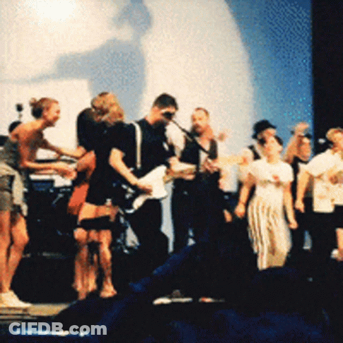 A Group Of People Are Standing On A Stage Playing Guitars GIF