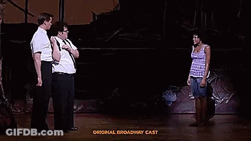 A Group Of People Are Standing On A Stage Talking To Each Other In A Play . GIF