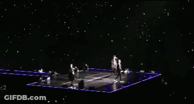 A Group Of People Are Standing On A Stage With A Lot Of Lights On It GIF