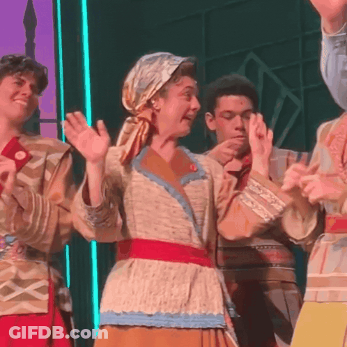 A Group Of People Are Standing On A Stage With Their Hands Up GIF