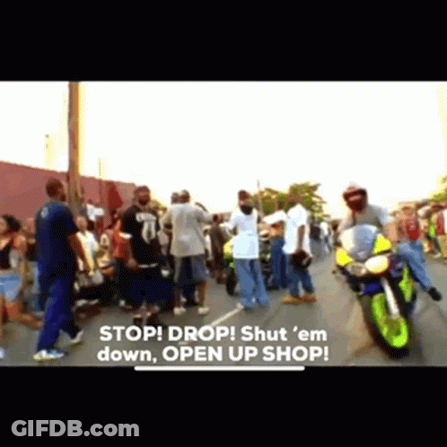 A Group Of People Are Standing On A Street With A Motorcycle In The Foreground And The Words Stop Drop Shut Em Down Open GIF
