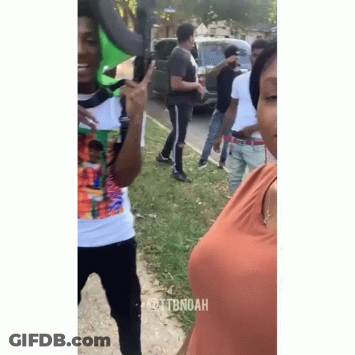 A Group Of People Are Standing On The Side Of The Road And One Of Them Is Giving The Peace Sign . GIF