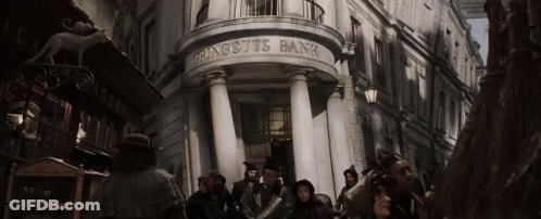 A Group Of People Are Standing Outside Of A Building That Says Gringotts Bank GIF