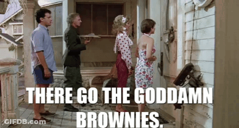 A Group Of People Are Standing Outside Of A House And A Man Is Holding A Tray Of Brownies . GIF