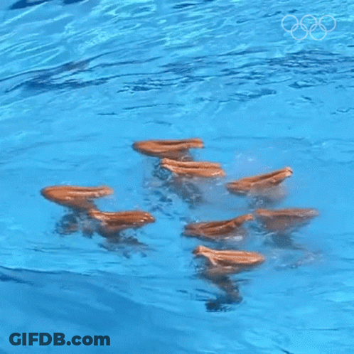A Group Of People Are Swimming In A Pool With The Olympic Rings Visible In The Background GIF