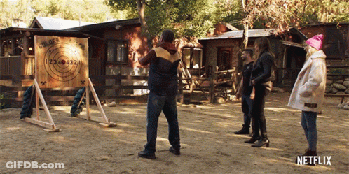 A Group Of People Are Throwing Axes At A Target That Says Golden Arrow GIF