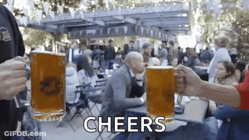 A Group Of People Are Toasting With Beer Mugs And The Words Cheers Are Visible In The Background GIF
