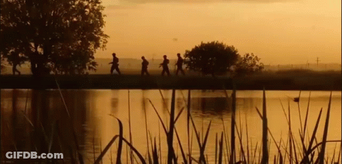 A Group Of People Are Walking Across A Lake At Sunset . GIF