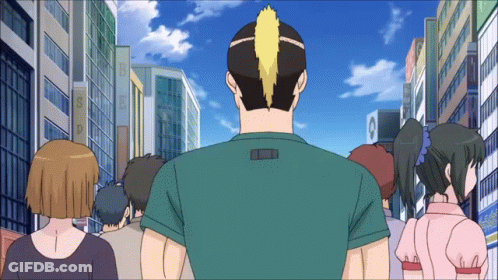 A Group Of People Are Walking Down A City Street With A Man Wearing A Green Shirt With The Letter L On It GIF