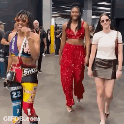 A Group Of People Are Walking Down A Hallway And One Of Them Is Wearing A Crop Top With The Number 22 On It . GIF