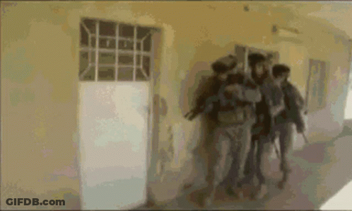 A Group Of People Are Walking Down A Hallway Holding Guns GIF