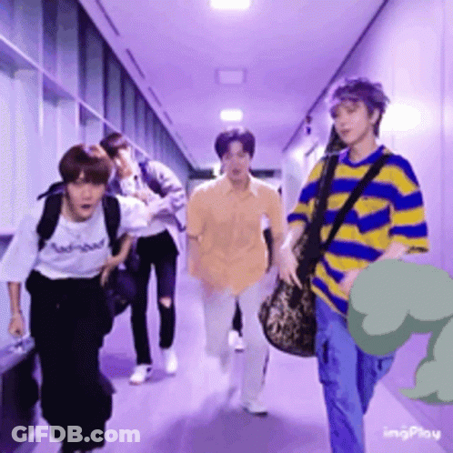 A Group Of People Are Walking Down A Hallway With A Dinosaur In The Background GIF