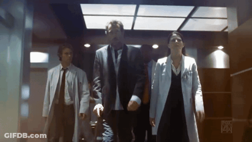 A Group Of People Are Walking Down A Hallway With Fox On The Bottom Right GIF