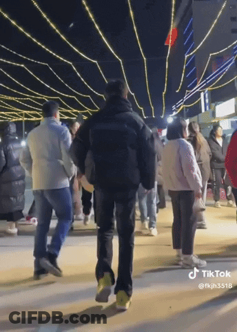 A Group Of People Are Walking Down A Street At Night With A Tiktok Watermark GIF