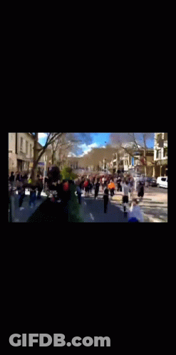 A Group Of People Are Walking Down A Street In A Blurry Photo GIF