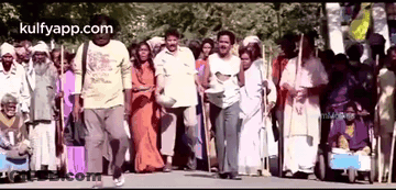 A Group Of People Are Walking Down A Street In A Crowded Area . GIF