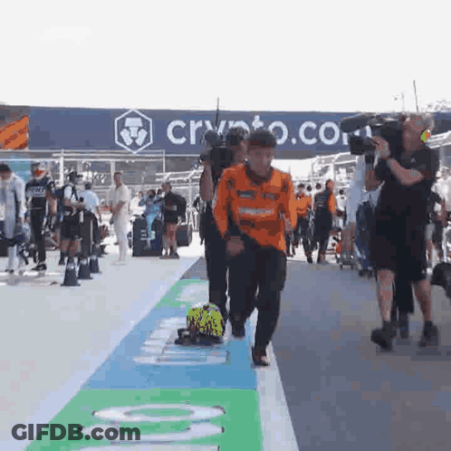 A Group Of People Are Walking Down A Street In Front Of A Sign That Says Crypto . GIF