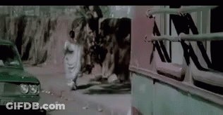 A Group Of People Are Walking Down A Street Next To A Car And A Bus . GIF