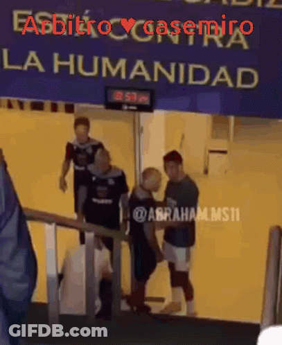 A Group Of People Are Walking Down Stairs Under A Sign That Says La Humanidad GIF