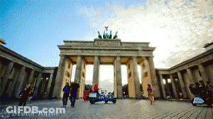 People Walking In Front Of Deutsch Sign GIF