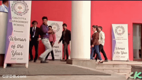 A Group Of People Are Walking In Front Of A Calcutta Management School Banner GIF