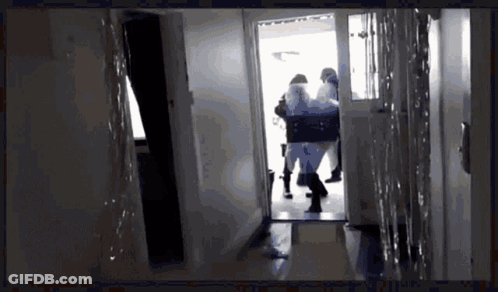 A Group Of People Are Walking Through A Hallway With A Silhouette Of A Person In The Background GIF