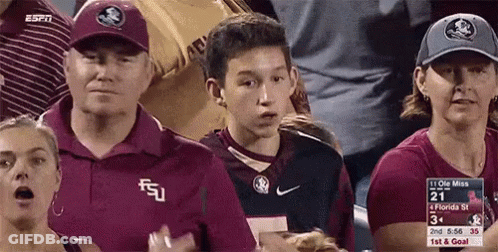 A Group Of People Are Watching A Football Game And One Of Them Is Wearing A Florida State Shirt GIF