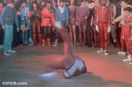 A Group Of People Are Watching A Man Do A Trick On A Dance Floor GIF