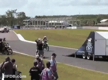 A Group Of People Are Watching A Race On A Track With A Trailer That Says Dry On It . GIF