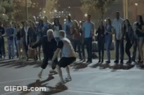 A Group Of People Are Watching Two People Play Basketball GIF