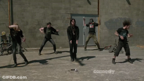 A Group Of People Dancing In Front Of A Comedy Sign GIF