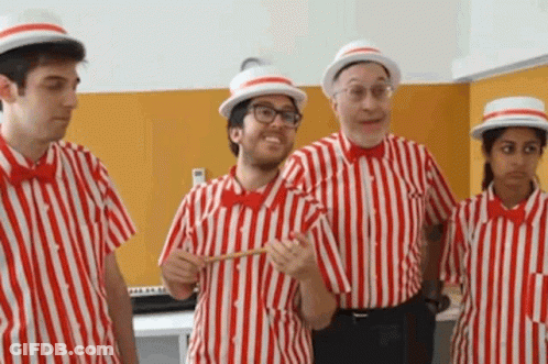 A Group Of People Dressed In Red And White Striped Shirts And Hats Are Standing Next To Each Other . GIF