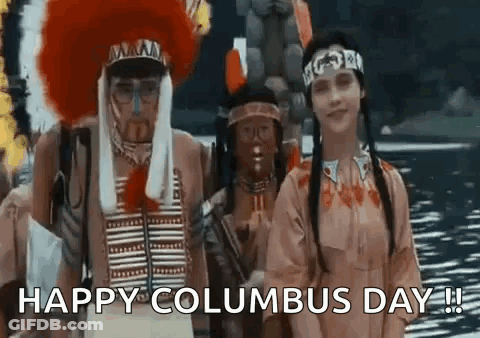 A Group Of People Dressed Up As Native Americans Are Standing Next To Each Other In Front Of A Body Of Water . GIF