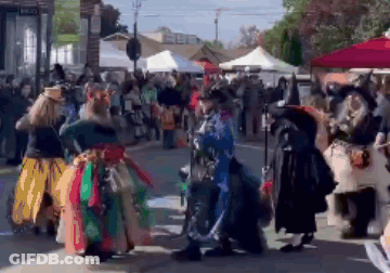 A Group Of People Dressed Up As Witches Are Dancing On A Street . GIF