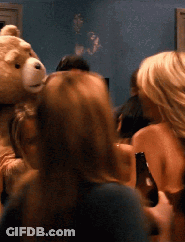 A Group Of People Gathered Around A Teddy Bear Holding A Beer Bottle GIF