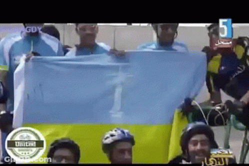 A Group Of People Holding A Flag With The Number 5 On The Bottom Right GIF