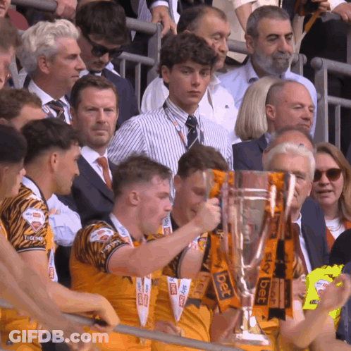 A Group Of People Holding A Trophy With Sky Bet Written On It GIF