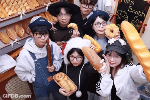A Group Of People Holding Bread And Donuts In Front Of A Sign That Says ' Turis Booth ' GIF