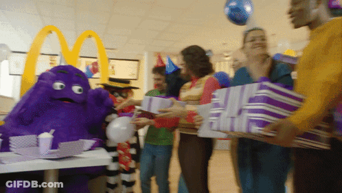 A Group Of People Holding Purple Gifts In Front Of A Mcdonald 'S Sign GIF