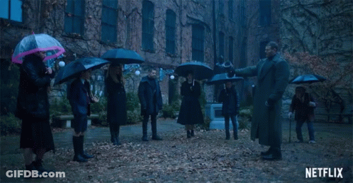A Group Of People Holding Umbrellas In Front Of A Building With Netflix Written On The Bottom GIF