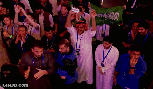A Group Of People Holding Up A Green Flag With Arabic Writing GIF