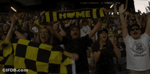 A Group Of People Holding Up A Scarf That Says " Home " GIF